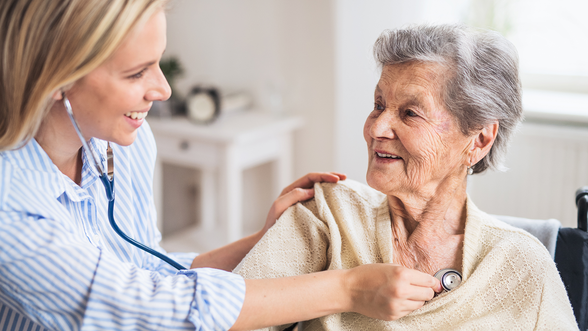 A nurse listens to an elderly patient's heart with stethoscope.