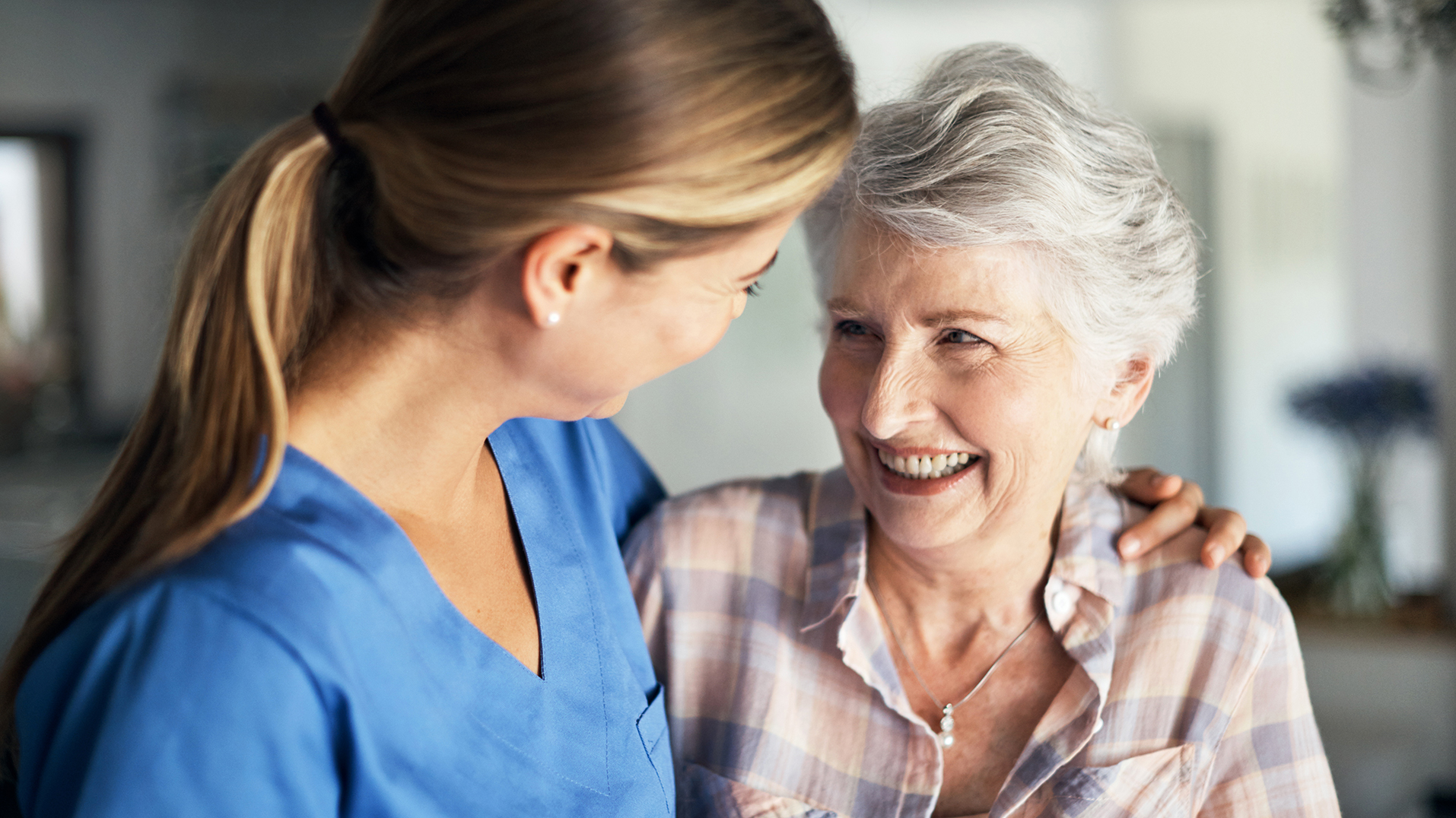 A nurse with arm around smiling patient.
