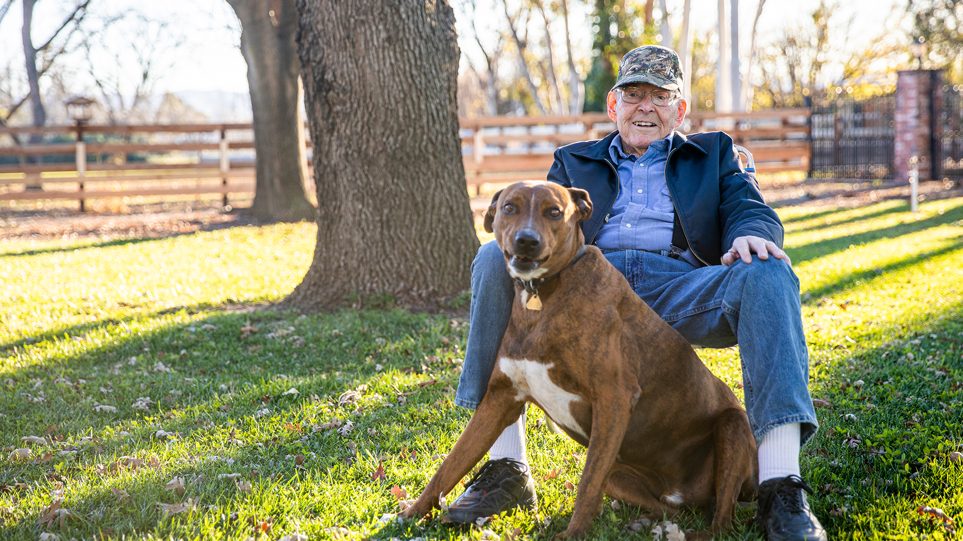 A veteran sitting in the yard with his dog.