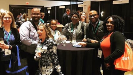 A small group of Kindred at Home associates smiling and talking at a conference.