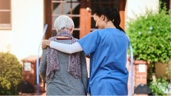 A home health aide with her arm around a patient.