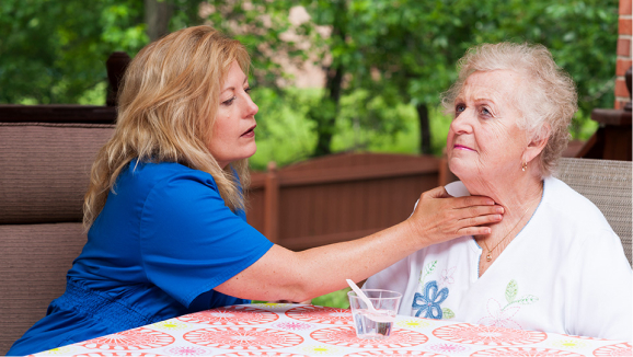 A speech therapist gently touching a patient’s throat. 
