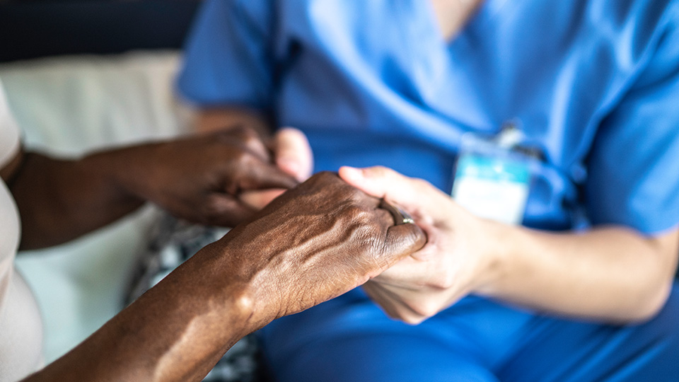 A nurse and a patient holding hands.