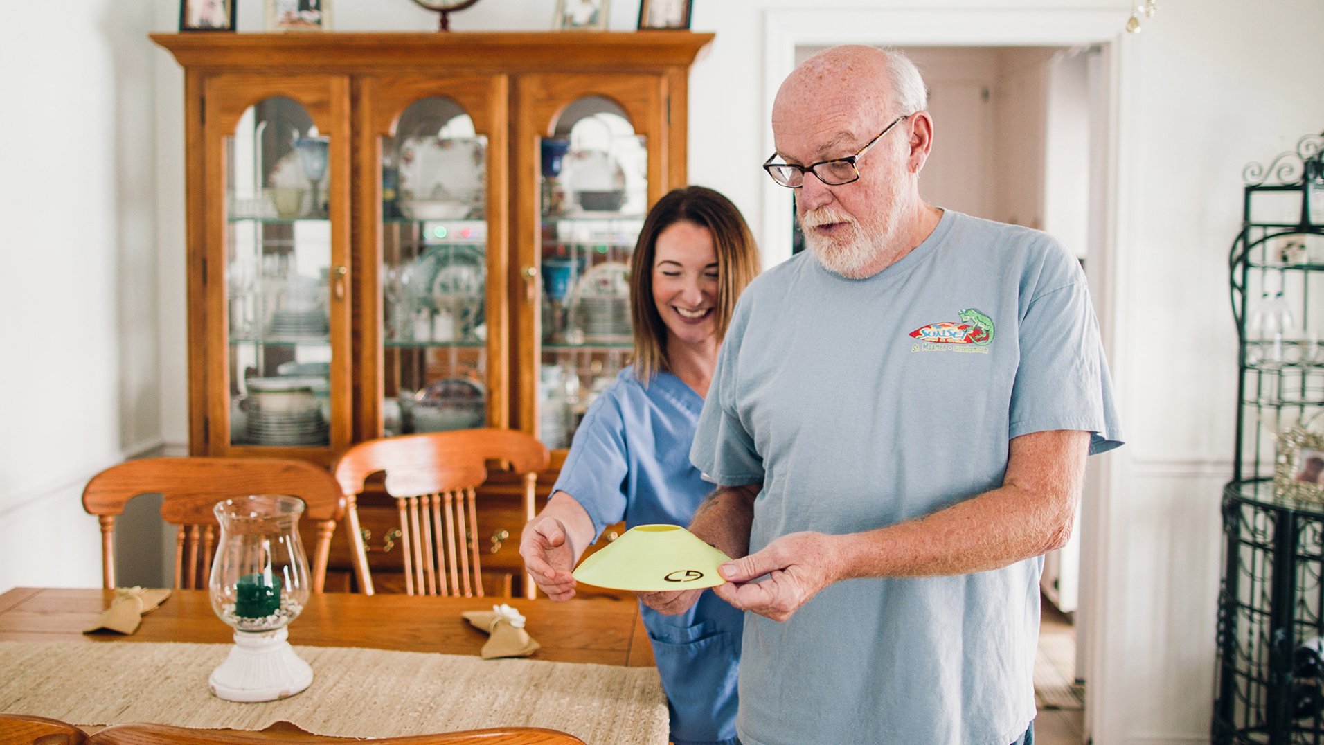 A therapist smiling and helping an elderly patient with an exercise.