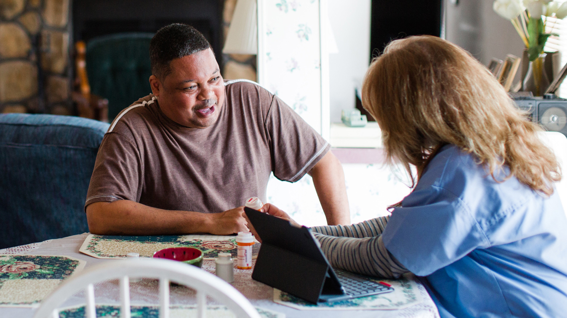 A home caregiver explaining information on a pill bottle to a patient.