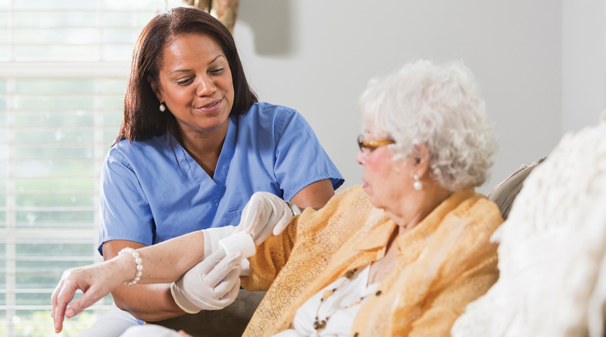 A caregiver gently applying a bandage to an elderly patient’s arm.